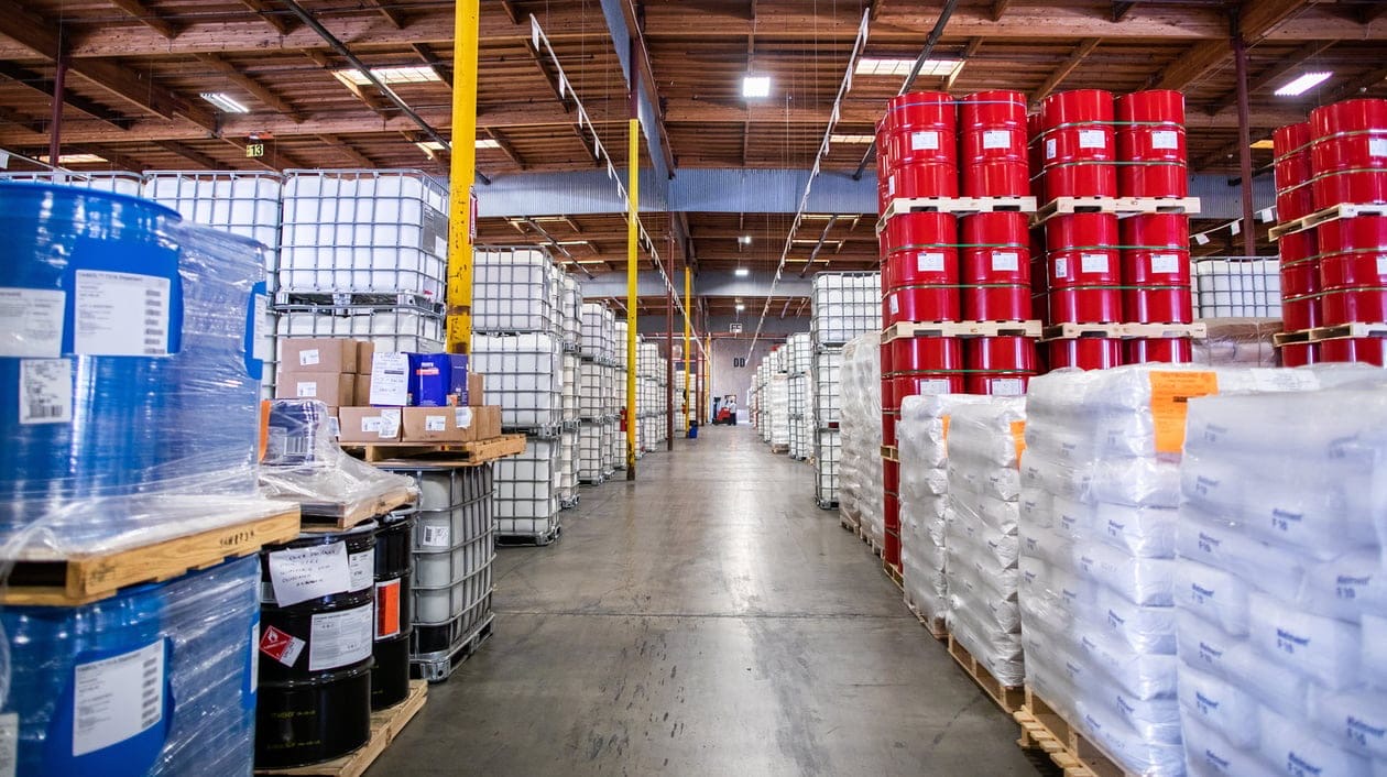 Interior of a chemical distribution warehouse with palletized drums and IBC totes