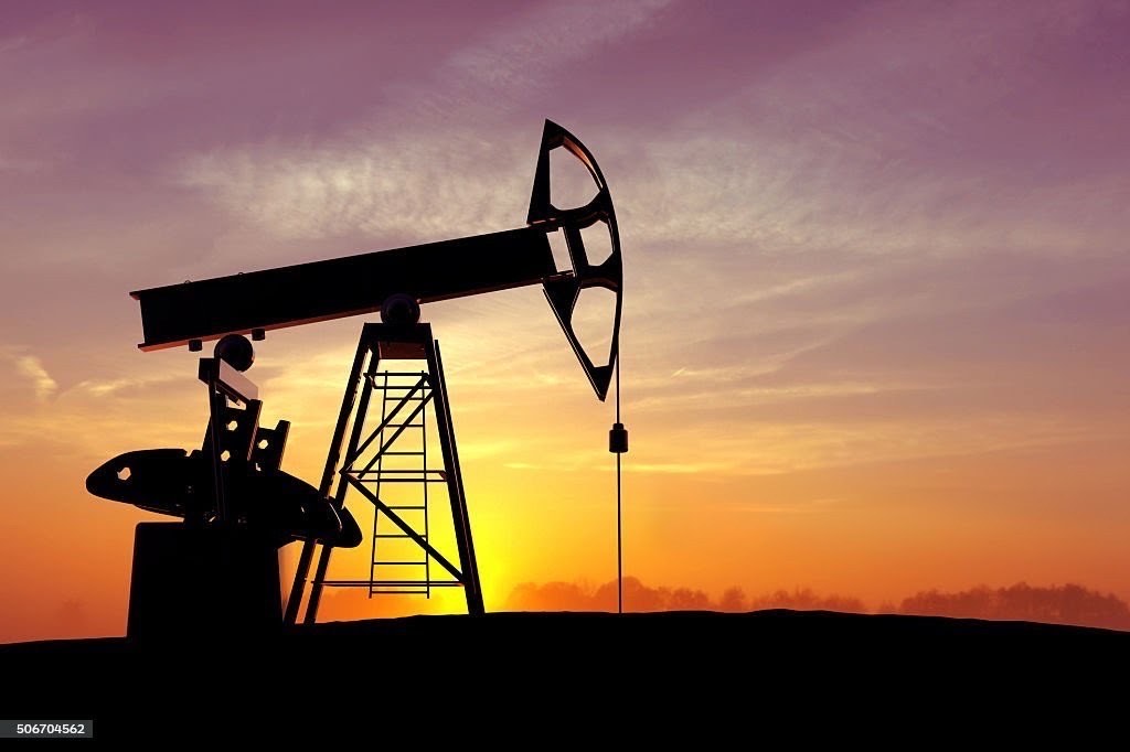 Oil pumpjack silhouetted against a desert sunset